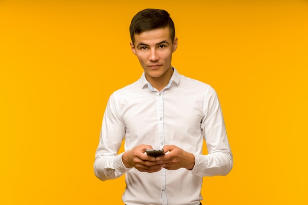 Asian man hold mobile phone after received bad news isolated on yellow space in studio. 