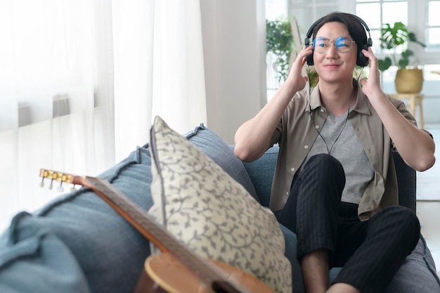 An asian man is listening Music in living room