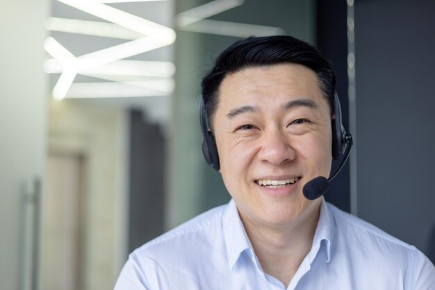 An asian man is pictured working intently in a welllit contemporary office exuding a professional