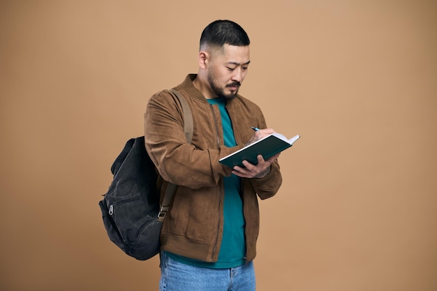 Asian man journalist in jacket making notes in notebook writing business idea