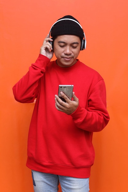 Asian man listening favorite music on mobile phone application with wireless headphones