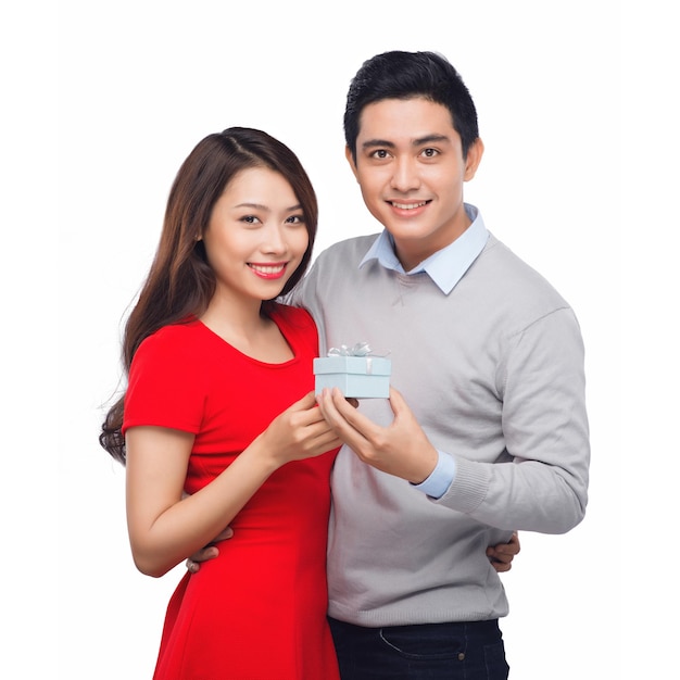 Asian man makes present to his lovely sweetheart. Young man giving a gift. Cheerful young couple man and woman at home offering to each other gifts for lover's valentine day