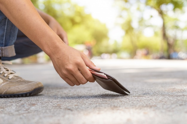 Asian man picking black wallet on the road in tourist attraction