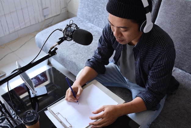 Asian man radio program host or blogger in headphones recording audio podcast using professional equ