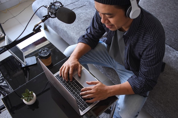 Asian man recording a podcast with headphone and microphone on his laptop. Podcaster making audio po