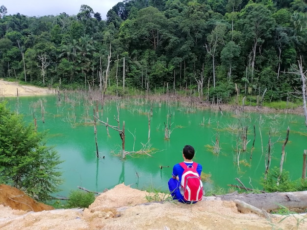 Asian man relaxing with serene view mountains and green lake landscape Vacations and travel lifestyle hiking concept.