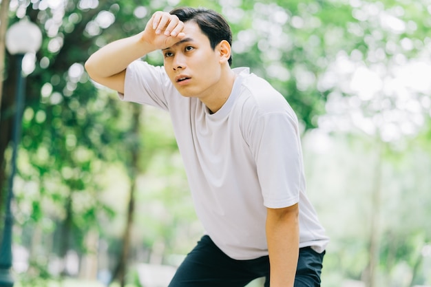 Asian man resting after jogging in park