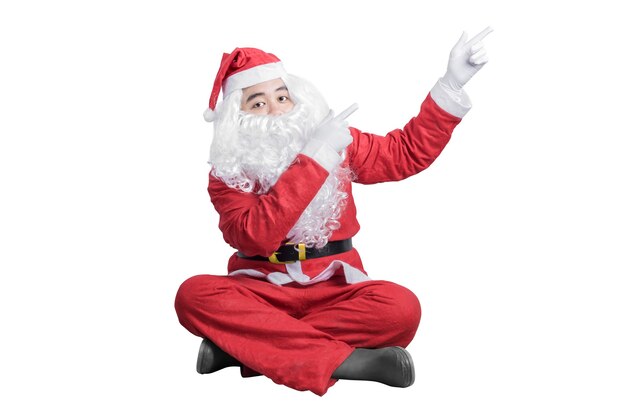 Asian man in Santa costume pointing something isolated over white.