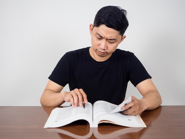 Asian man seriously about reading text book for test on the table