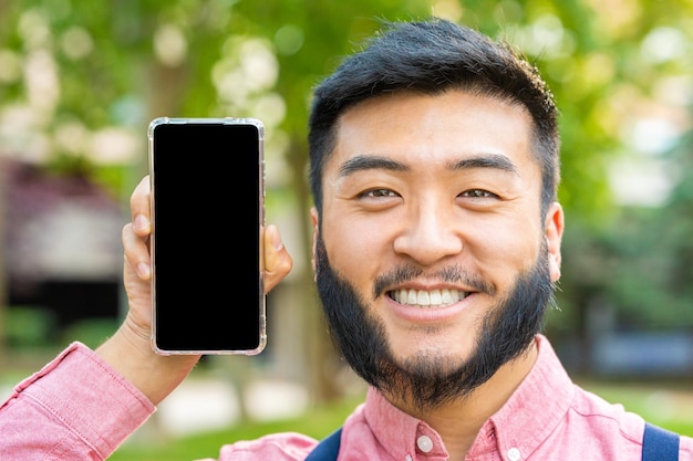 Asian man showing the screen of mobile phone while smiling