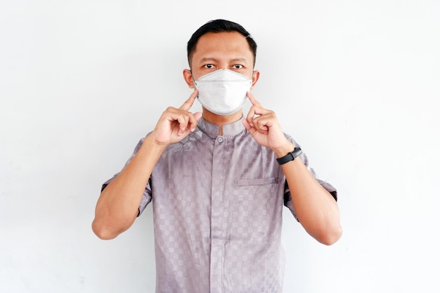 Asian man shows how to wear a mask isolated on white background.