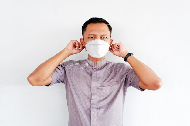 Asian man shows how to wear a mask isolated on white background