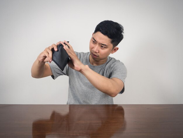 Asian man sitting and shake his wallet for finding moneyPoor man