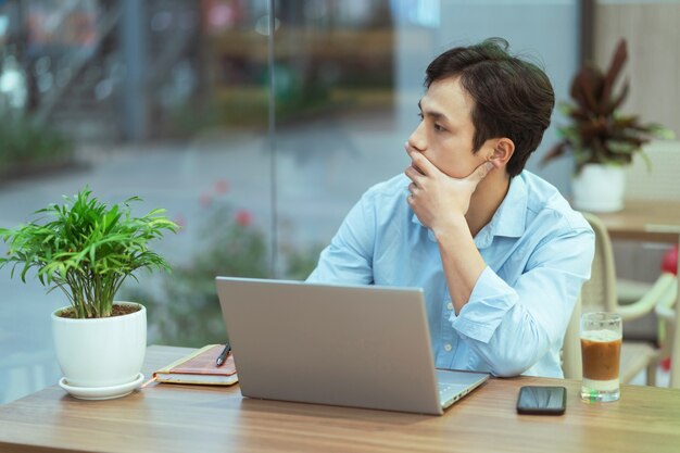 Asian man sitting working alone at a coffee shop