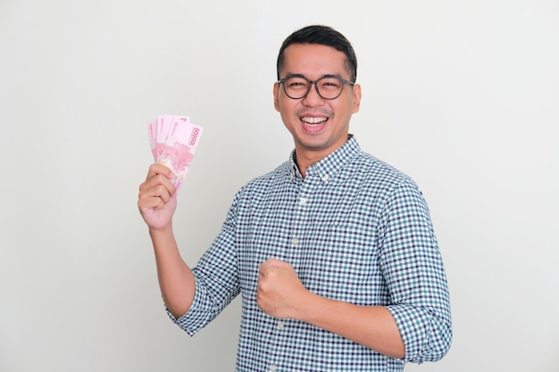 Asian man smiling to camera and clenched fist while holding money