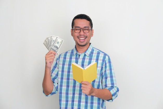 Asian man smiling happy while holding US dollar money and a book