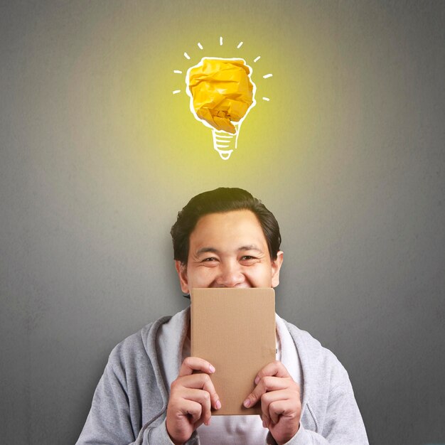 Asian man smiling happy with bright light bulb lamp made of paper symbol of idea and innovation