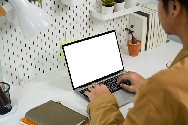 Asian man using laptop computer at modern workplace.