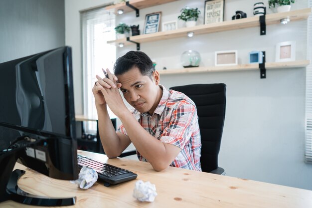 Asian man waiting for something looking at pc