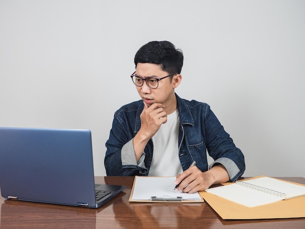 Asian man wear glasses working hard at workspace and using laptop