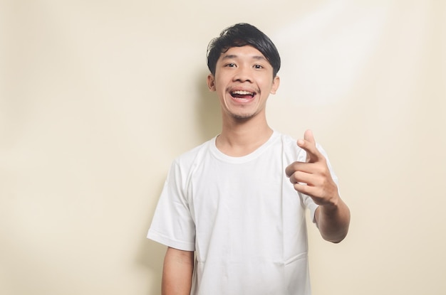 Asian man wearing white tshirt happy while pointing his hand forward isolated background