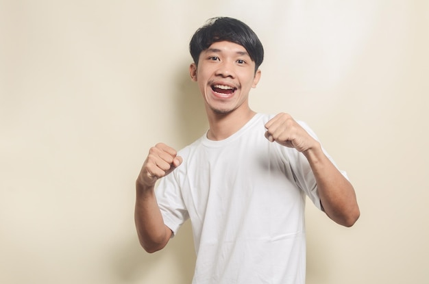 Asian man wearing white tshirt with happy gesture on isolated background