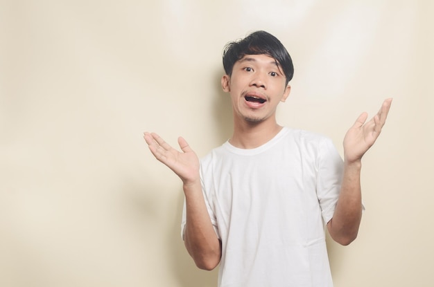 Asian man wearing white tshirt with surprised expression on isolated background