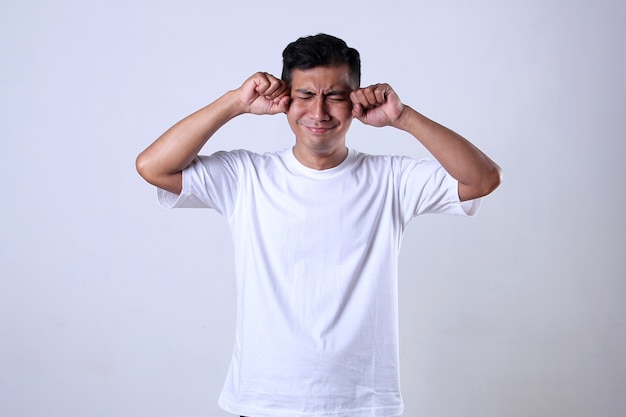 Asian man in white tshirt with funny crying expression Isolated on a white background