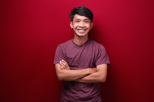 Asian man with crossed arms and looking forward on red background