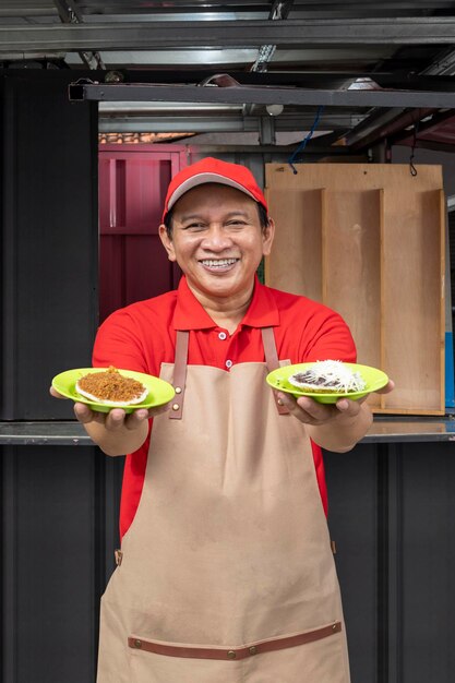 Asian man with a hat and apron showing serabi