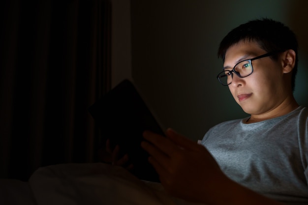 Asian man with laptop in his bed. Concept of technology, insufficient rest