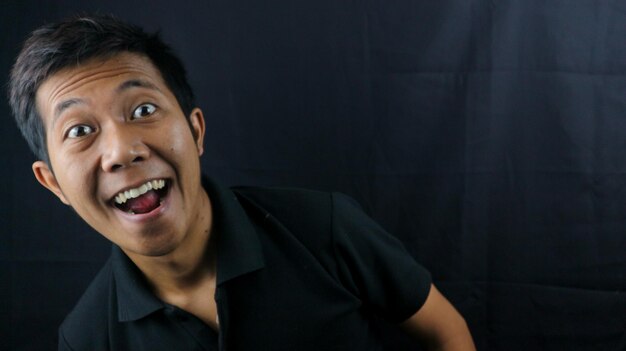 Asian man with laughing face on gray background Happy asian man smiling at camera giving thumbs up