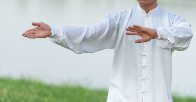 Asian man working out with Tai Chi in the morning at the park, Chinese martial arts, healthy care for life concept.