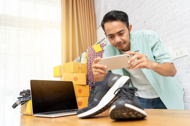 Asian man working taking photo to shoes with smart phone