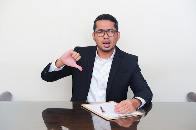 Asian manager wearing black suit give bad evaluation sign during interview process