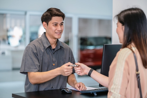 Asian mechanic recieving the automatic car key for checking at maintainance service center