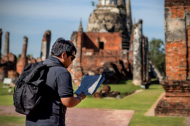 Asian men travelers looking map at a temple Phar sri sanphet Ayutthaya .