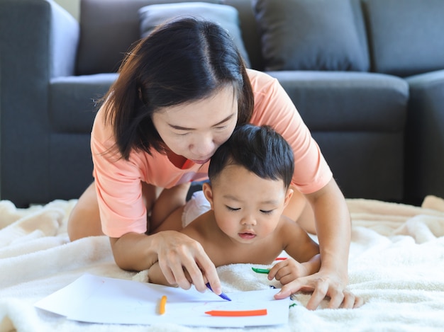 Asian mom teaching her baby boy draw