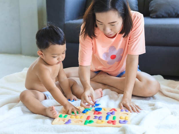 Asian mom teaching her baby boy. 
