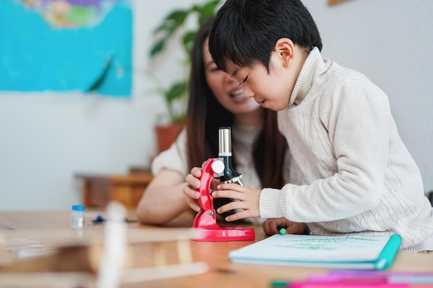 Asian mother and child having playful time with microscope toy