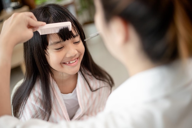 Asian Mother cutting hair to her daughter in living room at home while stay at home safe from Covid19 Coronavirus during lockdown Selfquarantine and social distancing concept