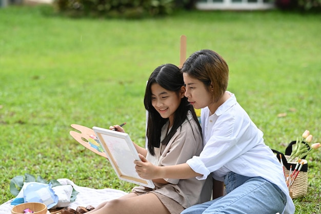 Asian mother and daughter painting together at the park