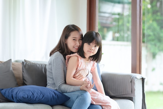 Asian mother feel hapiness during hug her cute daughter with love and care at home