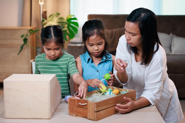 Asian mother and her daughters are decorating easter eggs preparing for Easter at home Happy family Happy easter Happy holiday