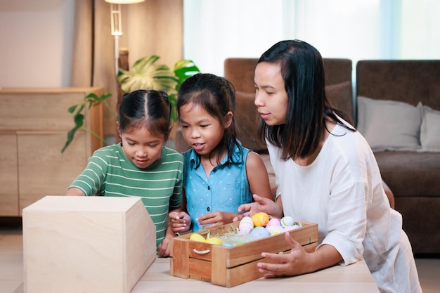 Asian mother and her daughters are decorating easter eggs preparing for Easter at home Happy family Happy easter Happy holiday