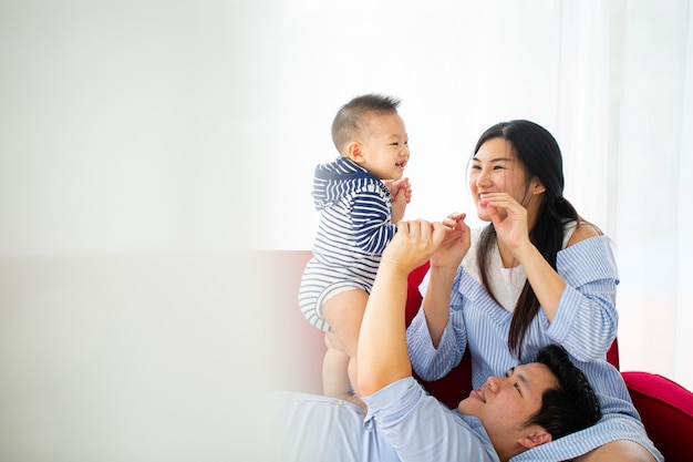 Asian mother holding her baby beside bedroom.