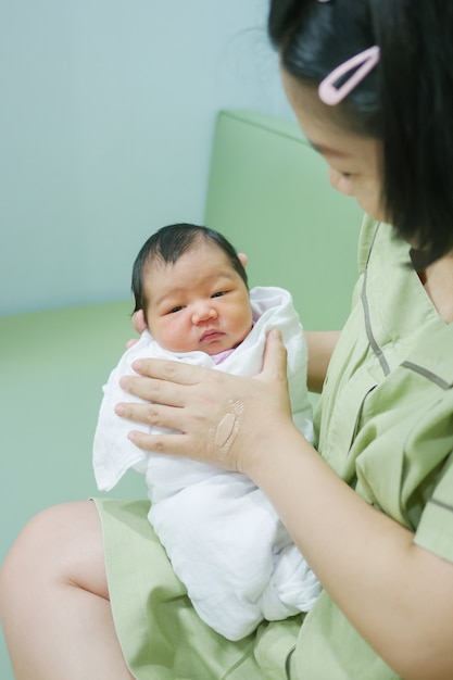 Asian mother holding her little daughter Her lovely daughter is opening her eyes