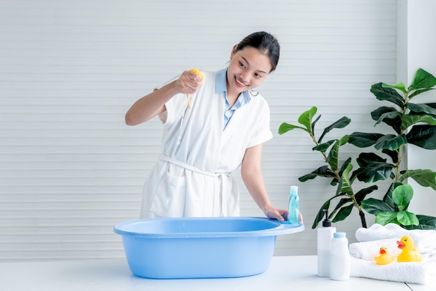 Asian mother is preparing toiletries and check the water temperature to bathe her child