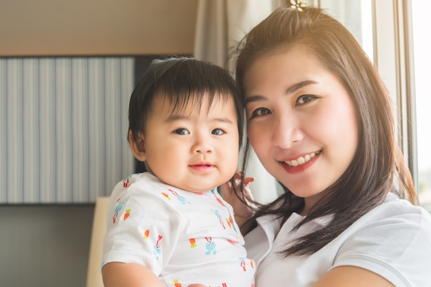 Asian mother playing with her baby in the bedroom.