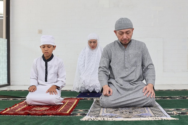 Asian muslim family praying salah jamaah together at home last movement on salat procedure